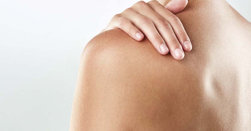 Frau legt Hand auf ihren Rücken